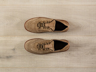 Sneakers in light suede lie on a light surface top view