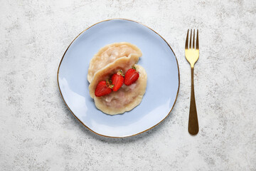 Plate with tasty strawberry dumplings on light background