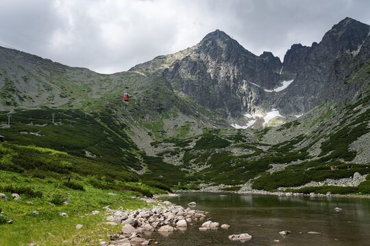 Scenic view of Skalnate Pleso (Rocky Tarn) and cable car heading to Lomnicky Stit peak in High Tatra mountains, Slovakia. Beautiful clean nature in Central Europe, cloudy day in summer