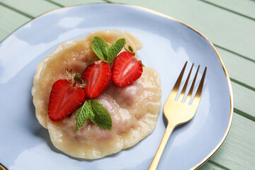 Plate with tasty strawberry dumplings on color wooden background, closeup