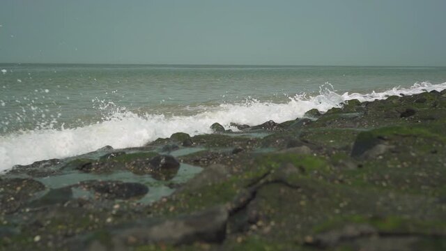 Medium wave hits rocky shore, slow motion.