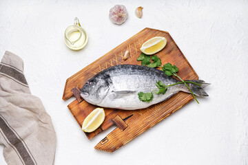 Board with raw dorado fish on light background