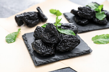 Slate plate with tasty prunes on dark background, closeup