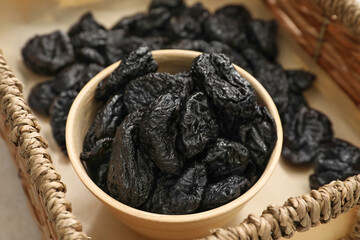 Bowl with tasty prunes on table, closeup