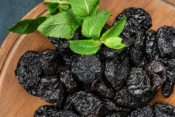 Board with tasty prunes on dark background, closeup