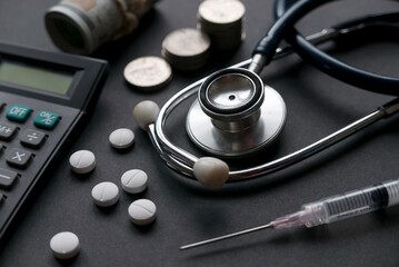 Healthcare and medical expenses concept. Stethoscope with pills, syringe,calculator,money and a stack of coins.