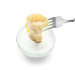 Fork with tasty dumpling and sauce on white background