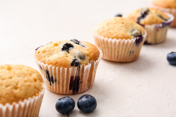 Tasty blueberry muffins on light background, closeup