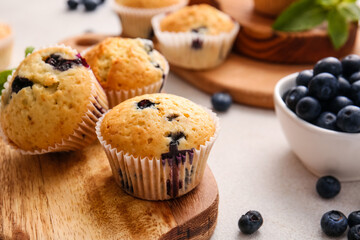 Tasty blueberry muffins and berries on light background, closeup