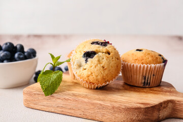 Board with tasty blueberry muffins on table
