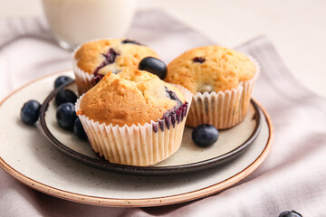 Plate with tasty blueberry muffins on table