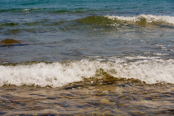 Waves with foam on Aegean sea coast in Crete Greece.