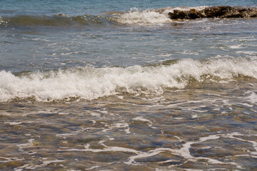 Waves with foam on Aegean sea coast in Crete Greece.
