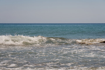 Waves with foam on Aegean sea coast in Crete Greece.