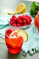 Glass with tasty raspberry lemonade on color wooden background