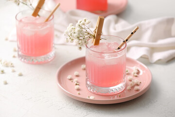 Glasses with tasty cocktail and beautiful gypsophila flowers on light background