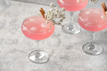 Glasses with tasty cocktail and beautiful gypsophila flowers on light background