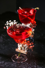 Glasses with tasty cocktail and beautiful gypsophila flowers on dark background