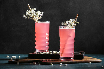 Glasses with tasty cocktail and beautiful gypsophila flowers on dark background
