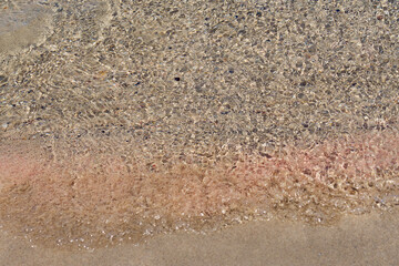 Clear waves and colorful sand on tropical sandy beach in Crete Greece.