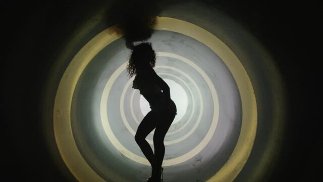 A silhouette of beautiful sexy girl , woman dancing inside circle tube . Against colored & gray background . Real decoration . None computer graphics . Shot on Arri Alexa Cinema Camera in 4K .