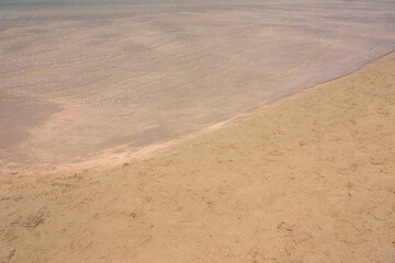 Clear waves and colorful sand on tropical sandy beach in Crete Greece.