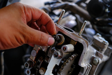 Fototapeta premium Set the valve on the cylinder head of the motorcycle engine by a technician.