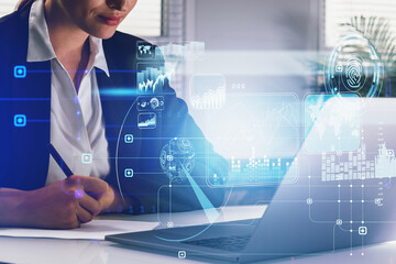 Businesswoman working in front of laptop taking notes, blue hologram glowing digital information security interface. Concept of cyber security and data storage. Fingerprint and business charts.