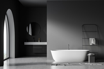 Fototapeta na wymiar Dark grey bathroom with arch window, vanity and oval bathtub