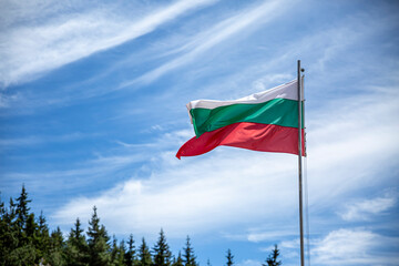 Bulgarian national flag on a pole against silky clouds.