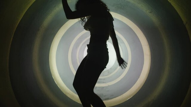 A silhouette of beautiful sexy girl , woman dancing inside circle tube . Against colored & gray background . Real decoration . None computer graphics . Shot on Arri Alexa Cinema Camera in 4K .
