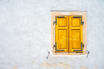 Old yellow window on blue wall with shutters
