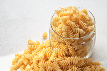 Italian quality uncooked durum wheat spiral pasta in glass jar on light background with copyspace