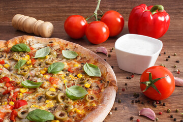 Vegetarian pizza and ingredients with spices on rustic wooden background, fast food