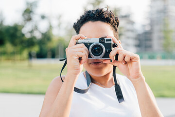 Young mixed race woman outdoors taking photo using camera collecting memories from holiday