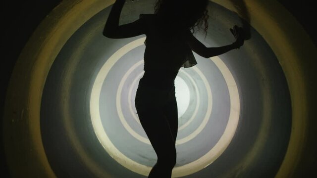 A silhouette of beautiful sexy girl , woman dancing inside round circle tube . Against colored & gray background . Real decoration . None computer graphics . Shot on Arri Alexa Cinema Camera in 4K .
