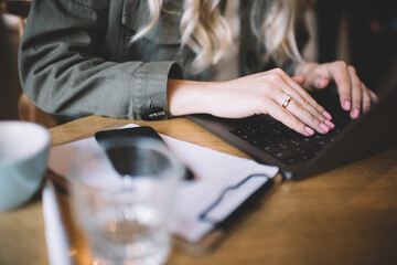 Faceless female using computer while working in cafeteria