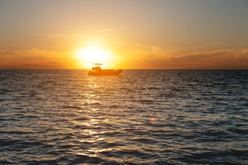 Naklejka na ściany i meble Small fishing boat catamaran at sunset. Sea transport without people in the sunset light. Twilight at sea