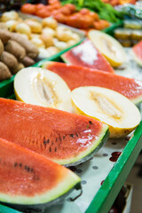 Vertical view of watermelon and melon portions displayed in a traditional food market.