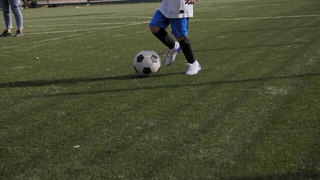 A little boy trains on the football field,he practices dribbling and goal kick