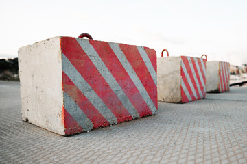 Fototapeta na wymiar Concrete road blocks with warning red and white diagonal stripes blocked the road.