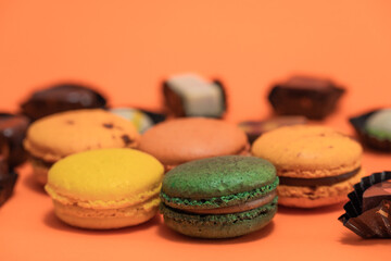 Close up of macaroons with some chocolates on an orange background