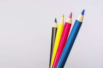 Four colored pencils. The colors cyan, magenta, yellow and black. The concept of polygraphy.