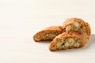 Traditional Italian almond biscuits (Cantucci) on white wooden table, space for text