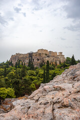 Acropolis (Parthenon, Propylaea, Temple of Athena Nike, Hekatompedon Temple) in summer greenery, Athens ancient historical landmark in city center with rocky Areopagus - Hill on cloudy day. Vertical