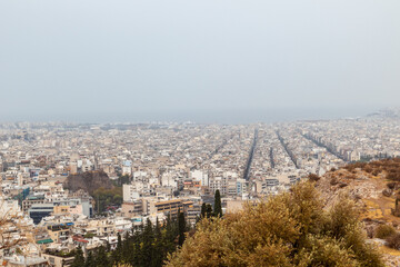 Athens city center streets with white buildings architecture on foggy day. Rooftop view from Filopappou Hill near Acropolis, Greece