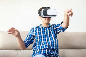 Teenage boy with VR glasses moving his arms and gesturing. Concept of new technologies at home.