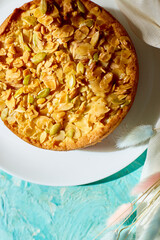 Apple or pear pie, tart with caramel nuts on blue table with sunlight