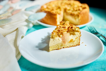 Piece of apple or pear pie, tart with caramel nuts on blue table with sunlight