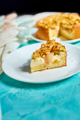 Piece of apple or pear pie, tart with caramel nuts on blue table with sunlight